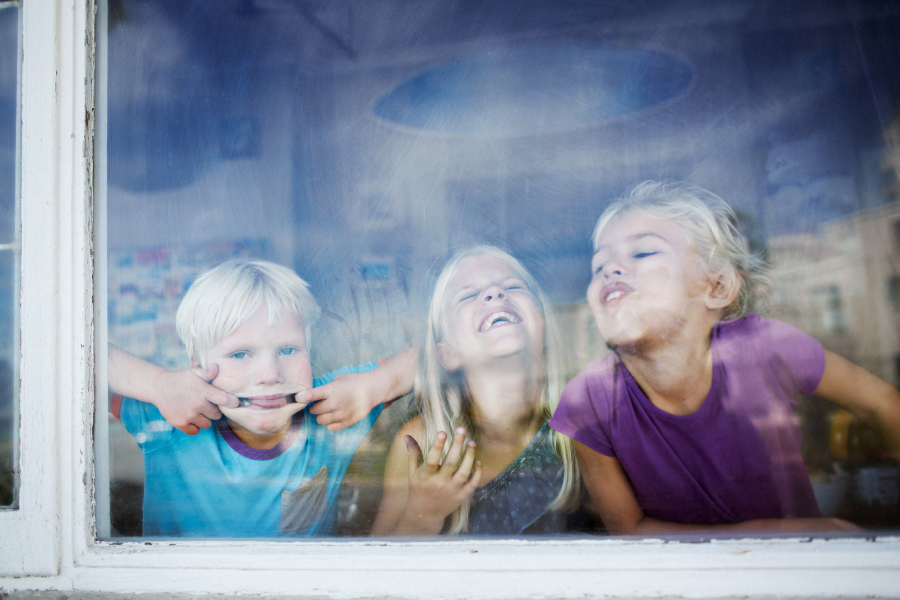 Kids making funny faces behind window