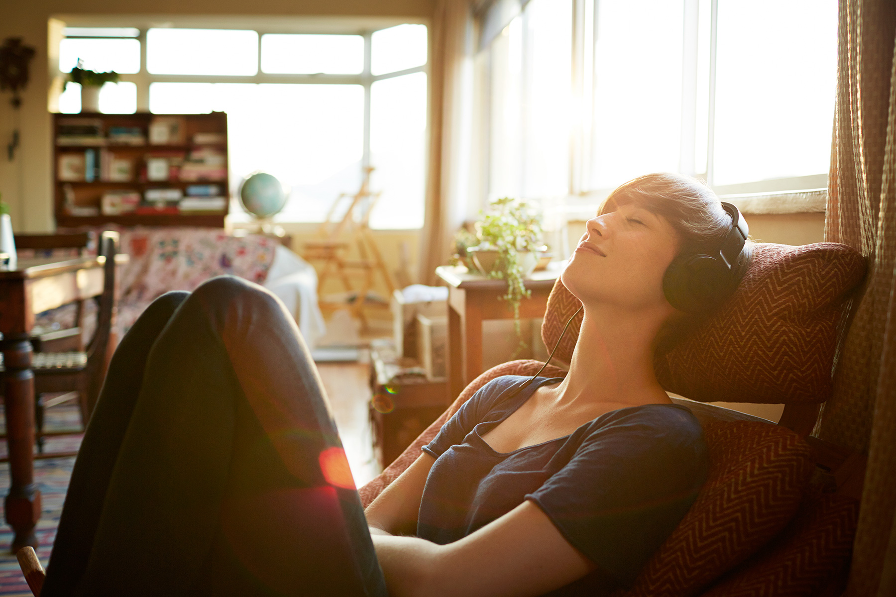 Woman with headphones relaxing at home in the sunset